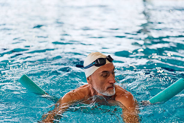 istock Senior man exercising in swimming pool using noodle float 2252057990