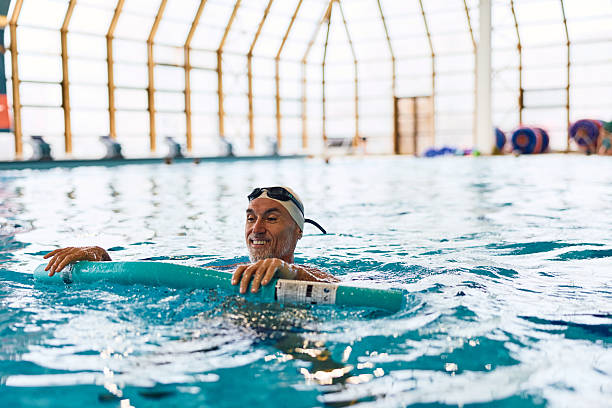 istock Senior man exercising in swimming pool with noodle 2252058067
