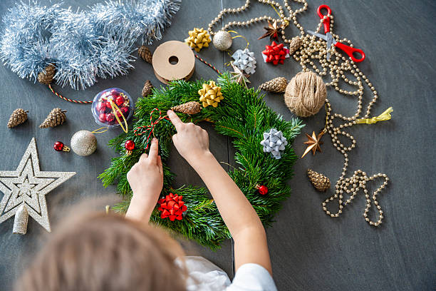 istock Little girl decorating a Christmas wreath while sitting at the table, top view. Capturing a hands-on festive activity from an overhead perspective at home. 2252060074