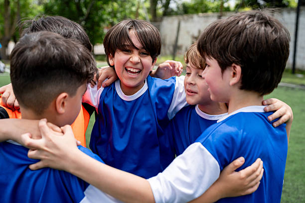 Happy Latin American soccer team hugging and celebrating a goal in the field and smiling