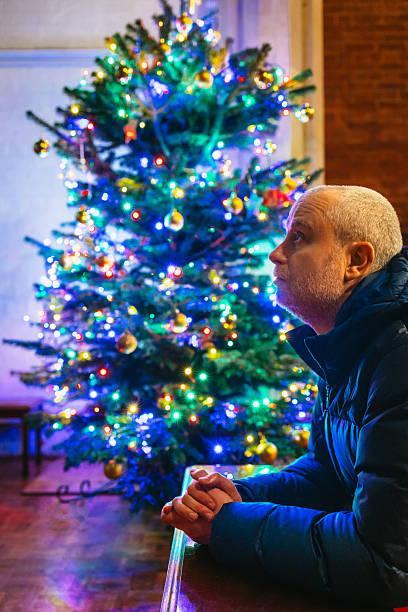 istock Man kneeling in prayer in church with illuminated Christmas tree 2252062662