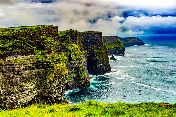 Colorful Green Grass Cliffs of Moher Claire County Ireland.  Cliffs tower up to 702 Feet over Atlantic Ocean and run for 9 miles along Irish coast. Unesco site one of most visited places in Ireland and site of many movies. Cliffs have nests of seabird.