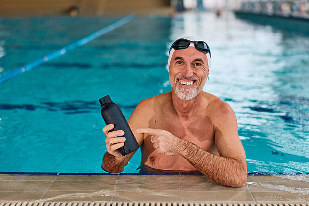 istock Senior man pointing at water bottle in swimming pool 2252064092
