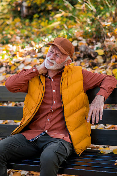 istock Senior man sitting on park bench with neck pain 2252066775