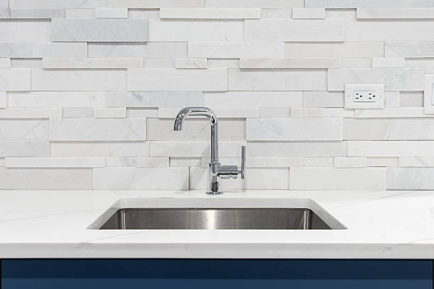 istock A kitchen faucet detail with a stone backsplash and blue cabinets. 2252068066