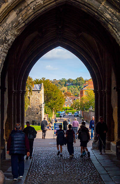 Dover Castle dominates the landscape, perched on a hill above a charming historic town with traditional English architecture. The scene is bathed in sunlight under a clear blue sky, capturing the essence of British heritage.