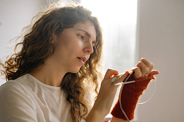 istock Woman knits with care while sitting near a window during daylight hours 2252068617
