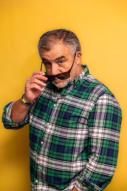 istock vertical Mature man looking over sunglasses on yellow background 2252068635