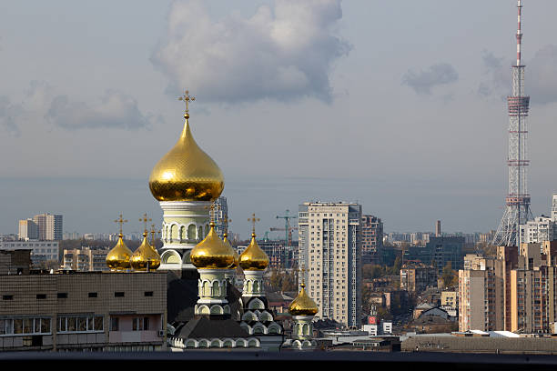 Pokrovsky Monastery domes and TV Tower landscape. Wide view of religious and industrial landmarks in Kyiv city skyline.