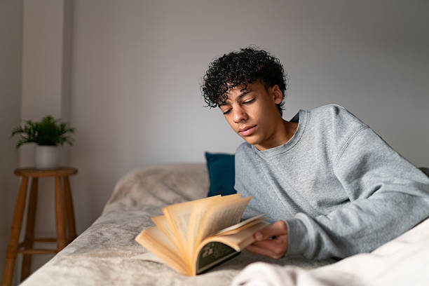 istock Teenage boy leafing through a book at home 2252069083