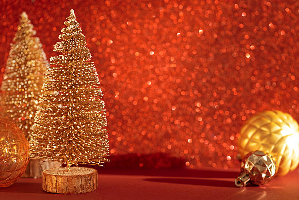 istock Golden Mini Christmas Trees with Ornaments on Red Glitter Background 2252072600
