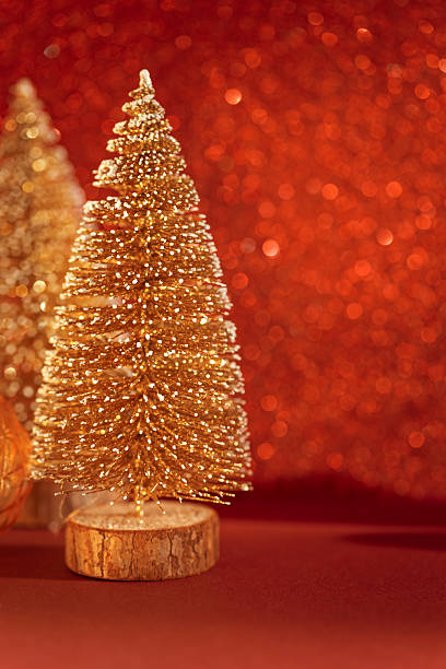 istock Golden Mini Christmas Trees with Ornaments on Red Glitter Background 2252072603
