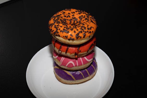 Multicolored donuts of various varieties on a black background. Pastry.
