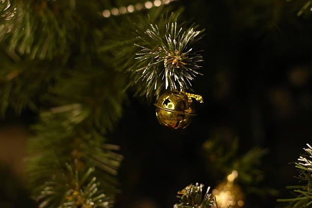 Close-up of a gold Christmas ornament hanging on an artificial Christmas tree. Festive holiday decoration.