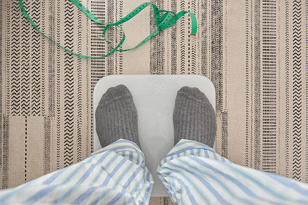 istock Person checking weight on scale for new year resolutions 2252080189