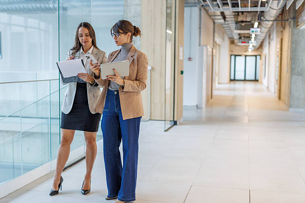 istock Businesswomen collaborating on document in modern office hallway 2252080826