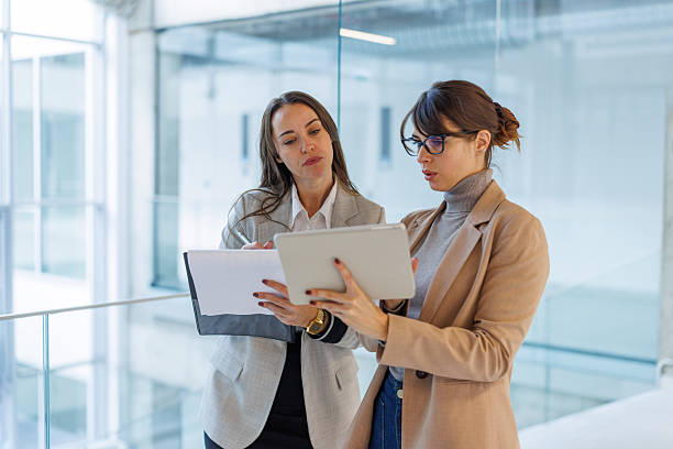 istock Businesswomen collaborating on digital tablet and documents in modern office 2252080836