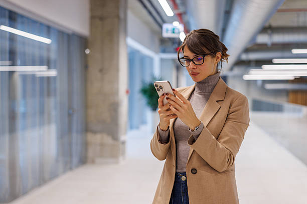istock Businesswoman standing in an office corridor, using a mobile phone 2252080847