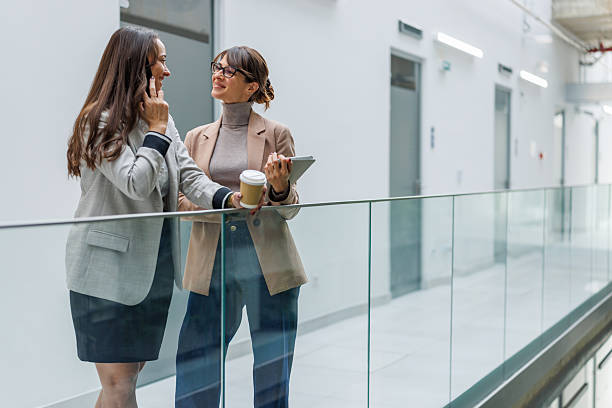 istock Businesswomen talking, drinking coffee in modern office hallway 2252080864