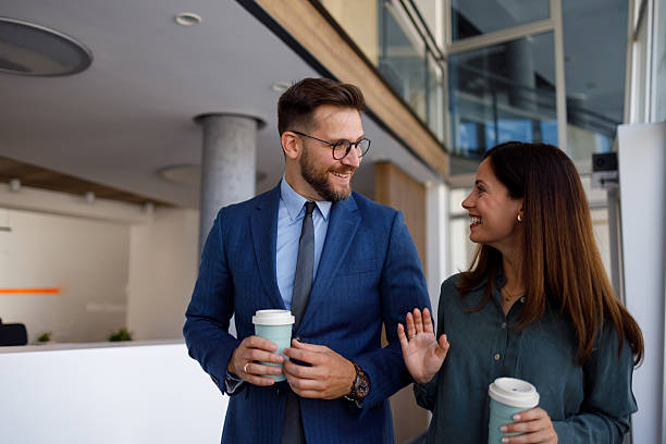 istock Business colleagues walking together, smiling while enjoying a coffee break in modern office building 2252080893