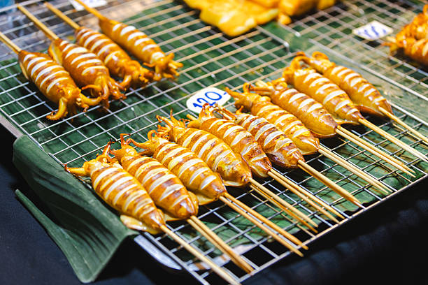 Barbecue calamari cooked on grill, Asian street food market view.Phuket Island - Thailand.