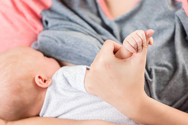 istock Mother tenderly holds newborn baby's hand while breastfeeding 2252086064