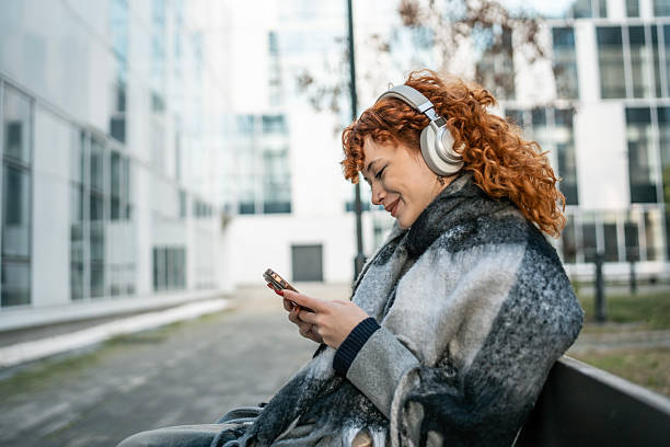istock Woman With Headphones Relaxing On Bench in Urban Setting While Using Phone 2252086641