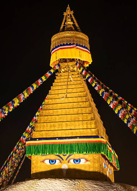 Boudhanath Stupa golden structure featuring Buddha's eyes and prayer flags at night