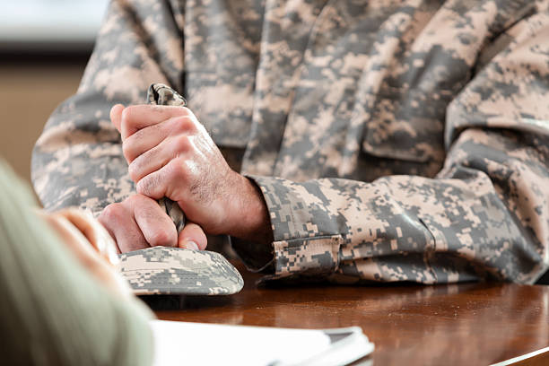 istock Veteran holds a camouflage cap, seeking support and guidance during a consultation. 2252089651