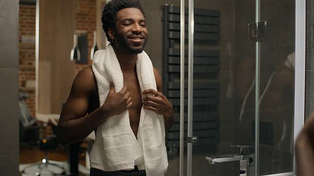 istock African American ethnic man in bathroom beard shaving face bearded guy looking at mirror reflection shave grooming morning hygiene smiling male facial moisturize lotion gel cream soft skin cosmetics 2252092567