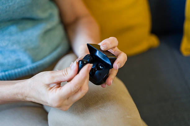Woman's hands removing wireless earbud from charging case while sitting on sofa