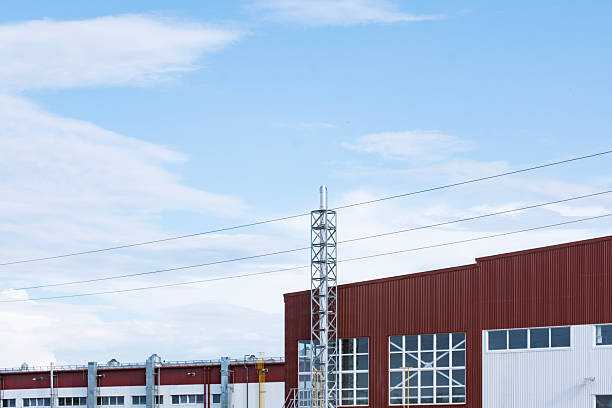 Contemporary industrial facility exterior featuring a red and white metal panel facade with silver exhaust or ventilation pipes. Concept modern industrial architecture
