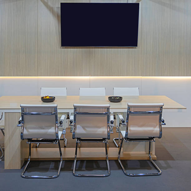 Wooden Desk With White Metal Chairs in Conference Room Office Space TV Set at Wooden Wall