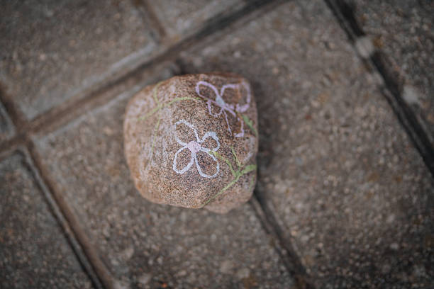 istock Decorative stone with colorful floral chalk drawings rests on a textured concrete surface, showcasing artistic expression and creativity in outdoor environments 2252099231