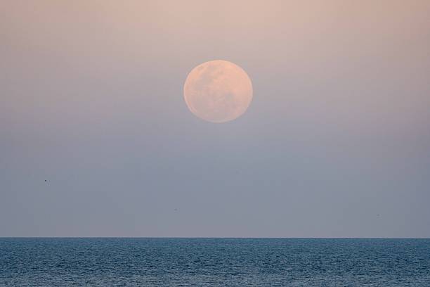istock A December supermoon rises above the ocean as the sun sets 2252103787