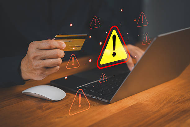 istock Customer hand holding a credit card while using a laptop with warning symbol, representing online payment risk, online shopping, financial fraud, or identity theft during digital transactions. 2252104769