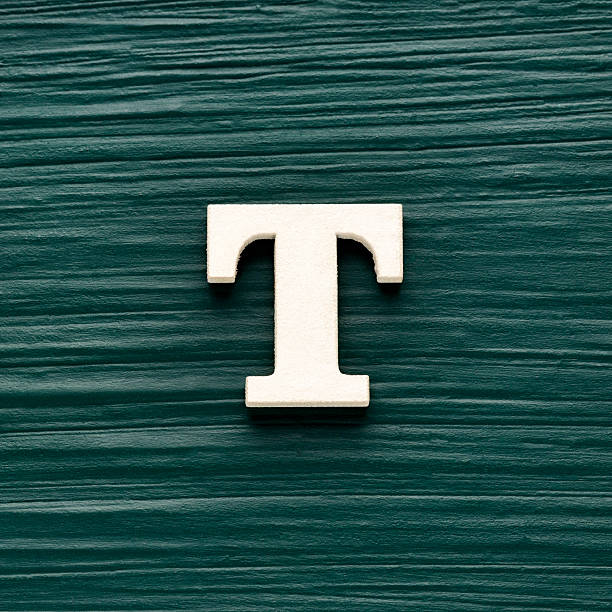 istock Alphabet letter T, white piece on a dark green rustic background 2252105539