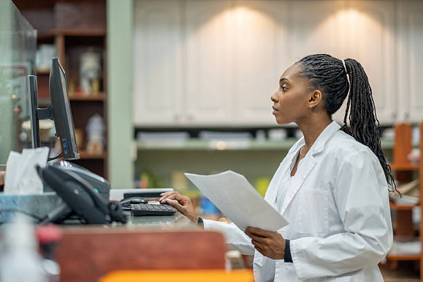 istock Black Female Scientist In White Lab Coat Working At Desk With Computer And Papers 2252110584