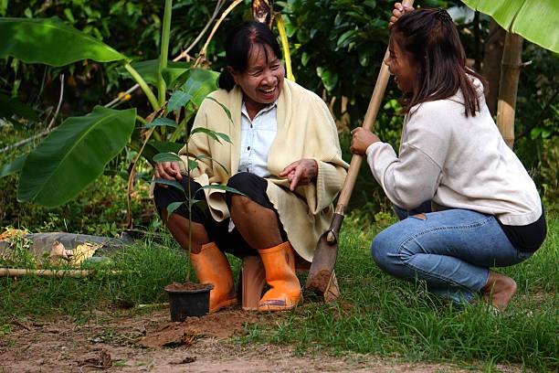 Two women sit talking and laughing joyfully after planting the tree.