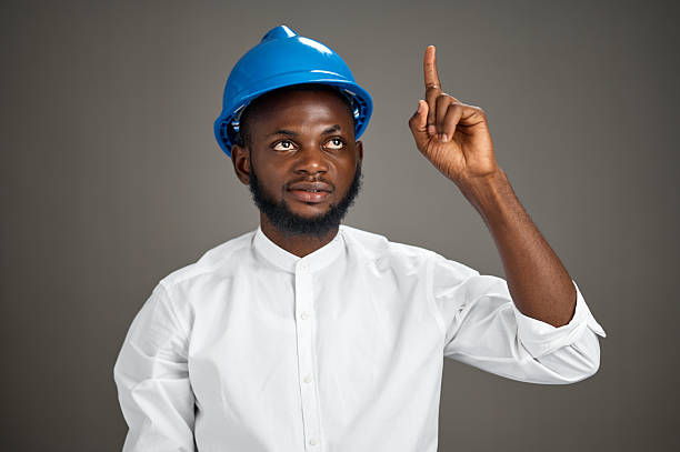 istock Young black man wearing blue safety helmet pointing upward in studio 2252117133