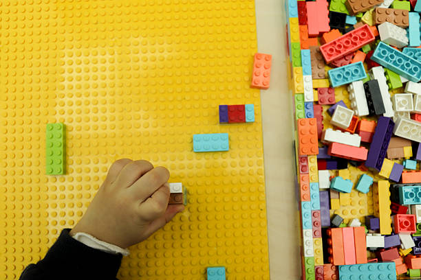 Child builds small towers with plastic blocks, learning balance and problem-solving skills.