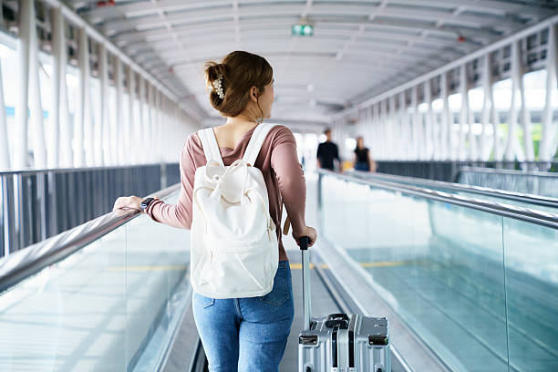 istock Woman pulling suitcase on moving walkway in airport terminal 2252124390