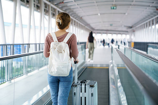 istock Woman pulling suitcase on moving walkway in airport terminal 2252124404