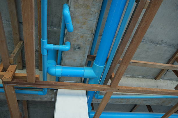 Blue pipes in a construction site with wooden framing and concrete walls