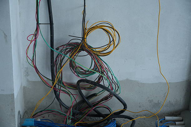 istock Messy colorful wires tangled on dirty wall in construction site 2252125579