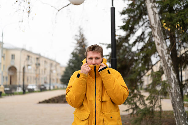 istock A man adjusts his yellow jacket while standing in a city setting with trees 2252133126