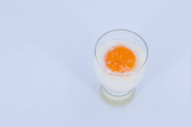 Soft boiled egg served in a clear glass with milk on a white background. Minimal studio food photography representing healthy breakfast, nutrition, and simplicity.
