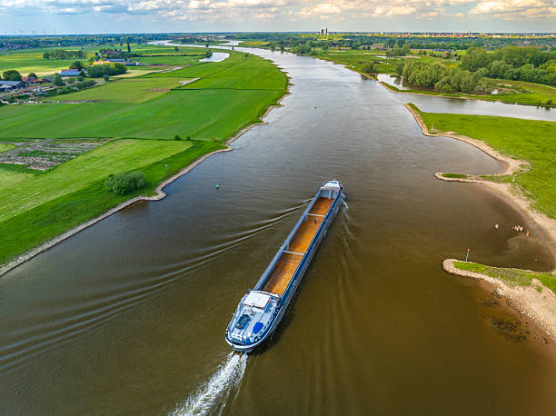 istock Freight ship sailing on the wide Ijssel River, creating a wake as it passes through vibrant green and yellow agricultural fields near Zwolle, Netherlands, on a bright spring day. 2252138317