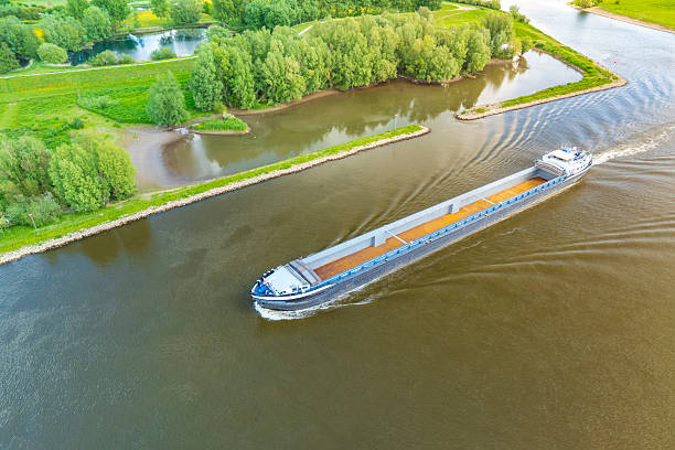 istock Freight ship sailing on the wide Ijssel River, creating a wake as it passes through vibrant green and yellow agricultural fields near Zwolle, Netherlands, on a bright spring day. 2252138318