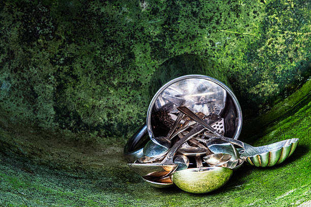 Silver spoons spilled from a container onto green patinated metal